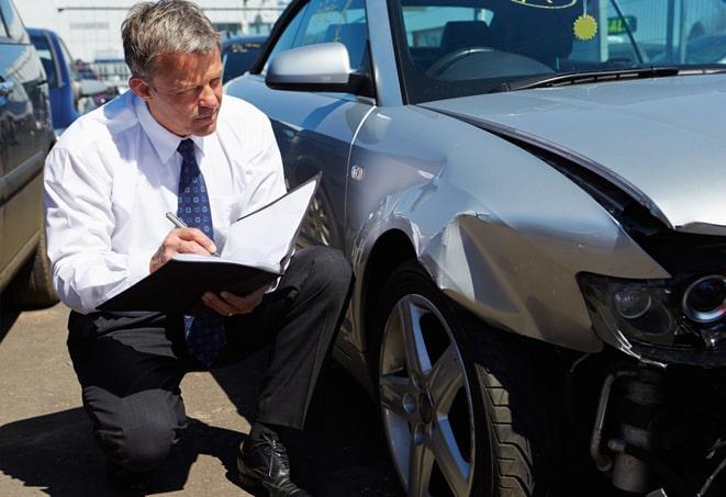 person signing car insurance document on desk